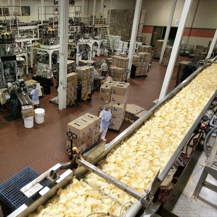 an assembly line in a factory filled with lots of boxes and people working on machines