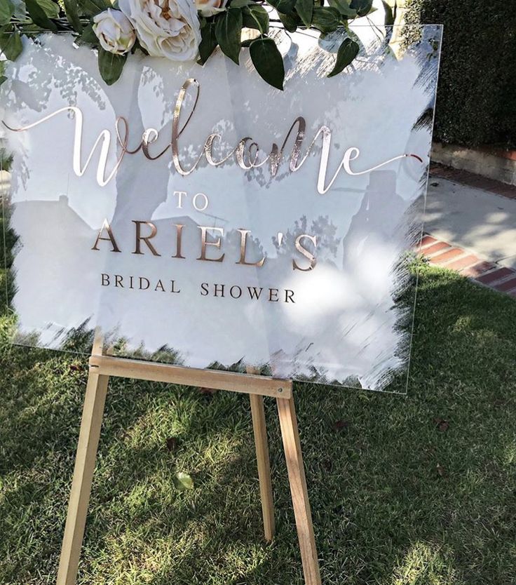 a welcome sign with flowers on it in front of a house for an arialis bridal shower