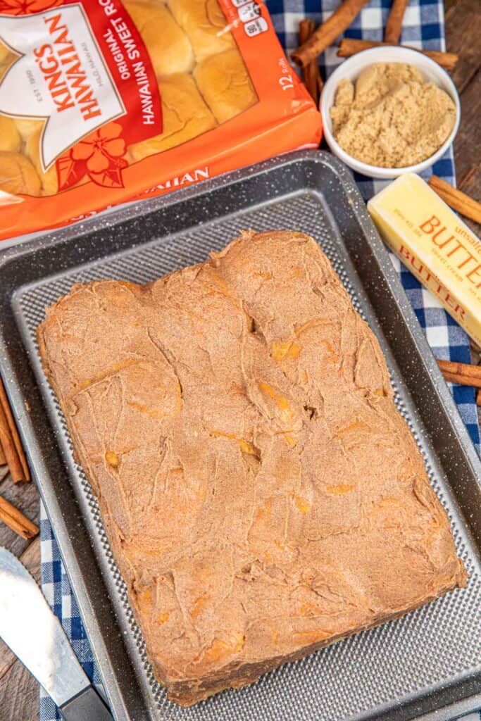 a baking pan filled with batter next to some cinnamon sticks and other ingredients on a checkered table cloth