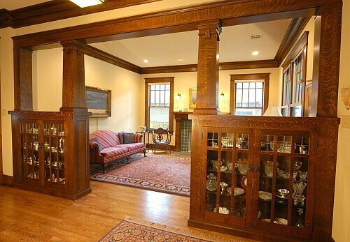 a living room filled with furniture and lots of wooden trim on the walls next to a fire place