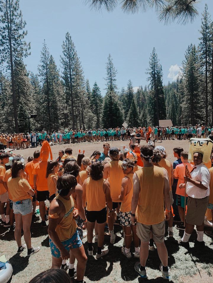 a group of people standing around each other in front of a forest filled with trees