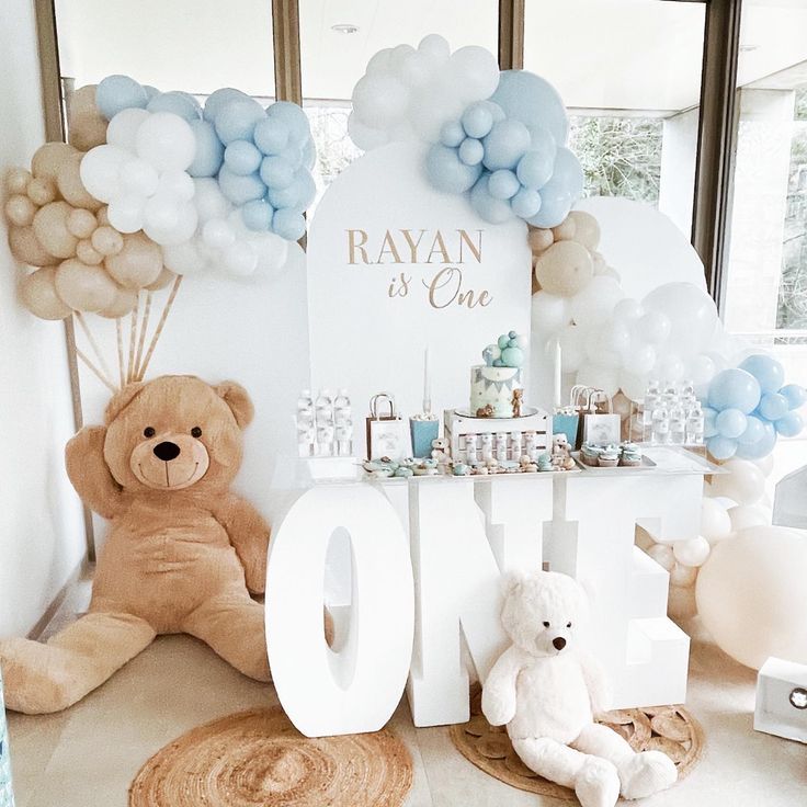 a teddy bear sitting in front of a table with balloons and other decorations on it