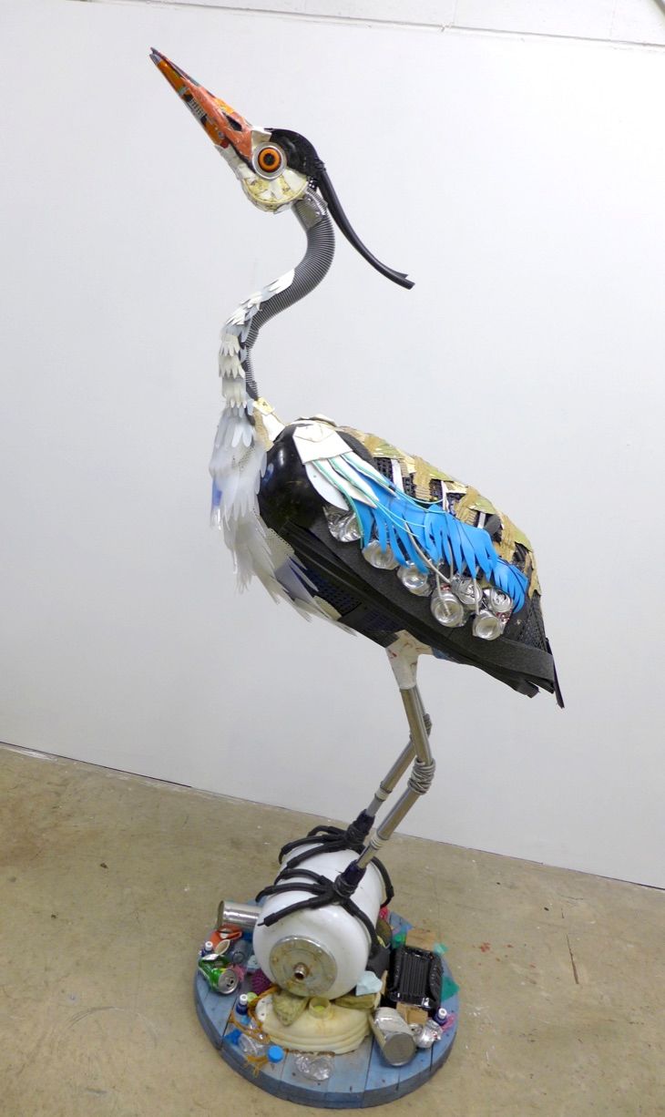 a statue of a bird with many things in it's beak and legs, standing on top of a table