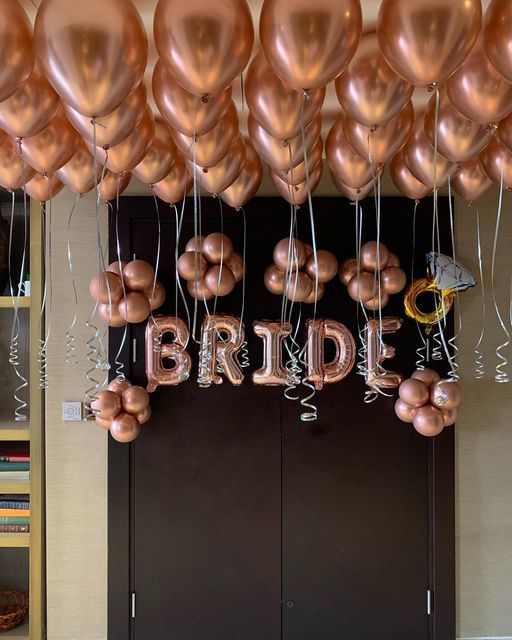 a bunch of balloons that are hanging from the ceiling in front of a bride sign