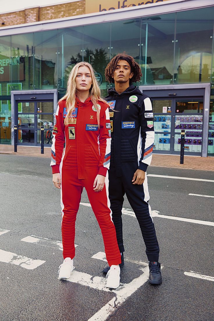 two people standing on the street in front of a shopping center wearing red and black outfits