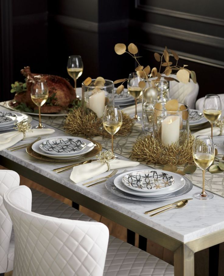 a dining table set with white and gold dishes