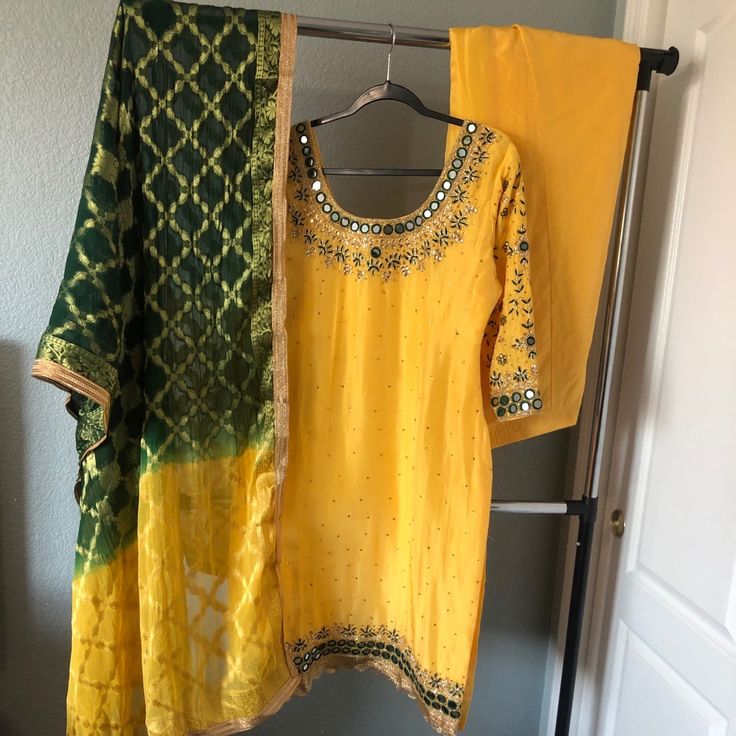 It’s A Yellow Top With Mirror/ Stone Embroidery Top With Full Work On Sleeves. Comes With Matching Yellow Salwar, And Ombr Emerald Green/ Yellow Chunni. Brand New. Estimated Measurements: Suit- Bust 40, Waist 42, Length 42 Salwar Length: 43. Margins 2 1/2’ Each Side Outfits Will Not Fit Into A Standard Size Category, All Of The Outfits Are Custom Made. *Most Outfits Are Pre Worn Unless Stated. Worn Items Will Show A Few Signs Of Wear Including Minor Stains, Missing Stones Around The Heavy Pieces Elegant Yellow Salwar Kameez With Dabka Work, Elegant Yellow Salwar Kameez For Festive Occasions, Elegant Yellow Salwar Kameez With Resham Embroidery, Yellow Dabka Work Sets For Summer, Party Yellow Salwar Kameez With Dabka Work, Yellow Sets With Dabka Work For Summer, Yellow Embroidered Silk Traditional Wear, Embroidered Yellow Silk Traditional Wear, Fitted Yellow Salwar Kameez With Dabka Work