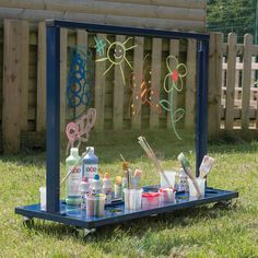 an outdoor art display in the grass with paints, brushes and other crafting supplies