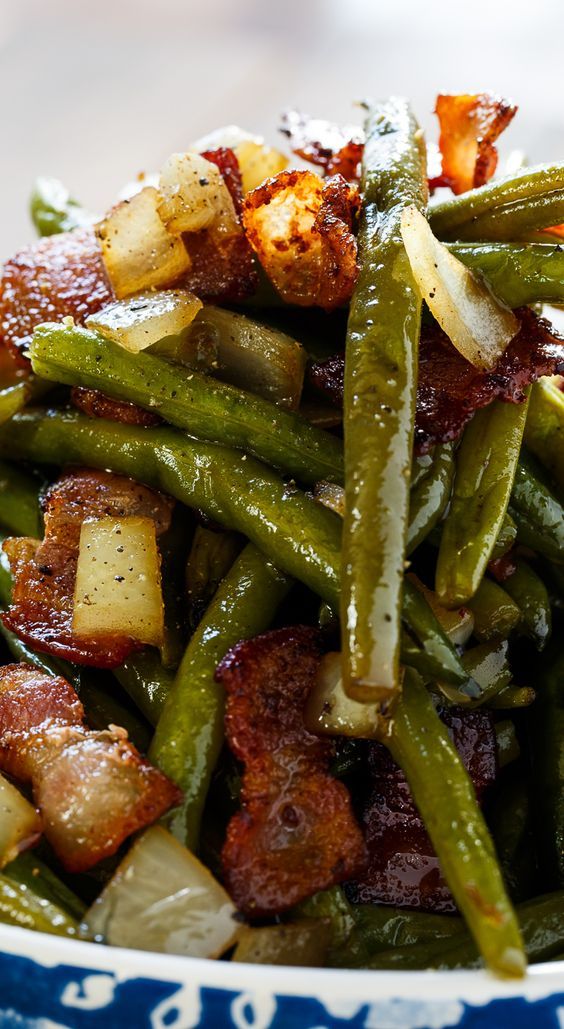 green beans, bacon and potatoes in a blue and white bowl on top of a table