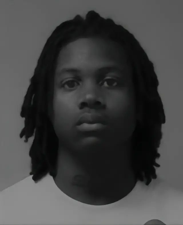 a black and white photo of a man with dreadlocks looking at the camera