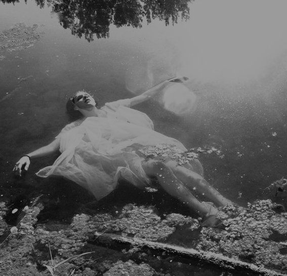 a black and white photo of a woman floating in the water