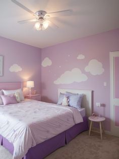 a bedroom decorated in purple and white with clouds painted on the wall above the bed