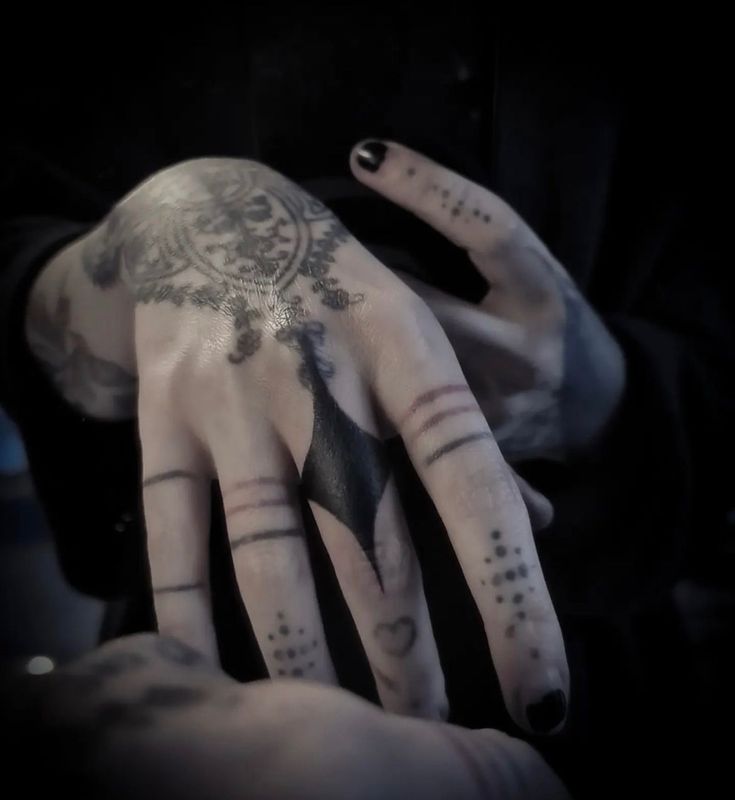 a person's hand with tattoos on it, and the other hand is covered in black ink