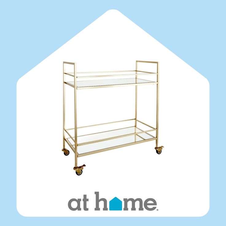 a gold serving cart with glass shelves on wheels and the words at home above it