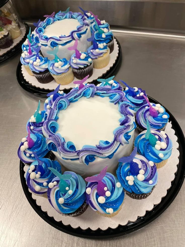 two cupcakes on plates with blue and white frosting, sitting on a counter