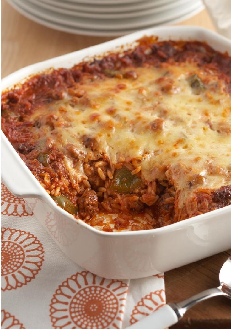 a casserole dish with meat and cheese in it on a wooden cutting board