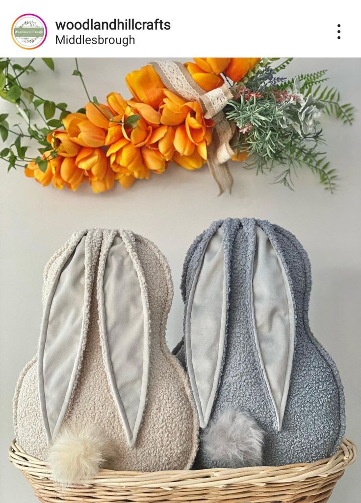 two bunny ears are sitting in a basket next to flowers and an orange flower arrangement