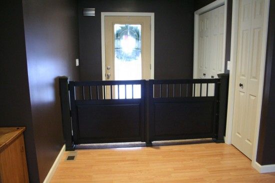 an empty room with a wooden floor and black fence in front of a white door