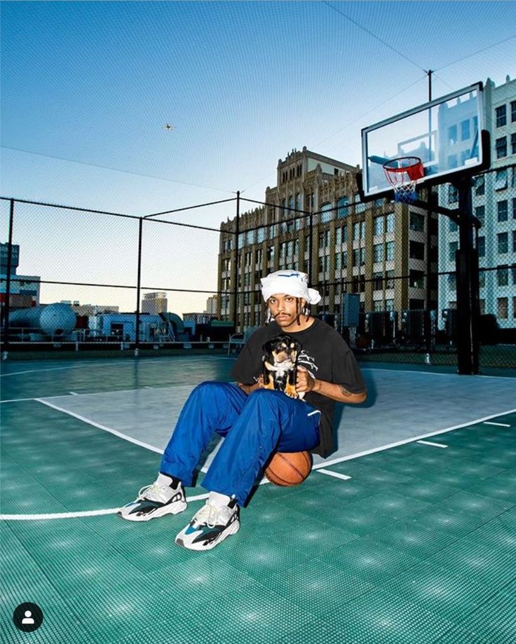 a man sitting on top of a basketball court next to a hoop with a ball in his hand