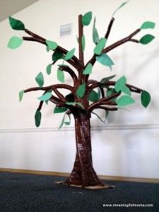 a tree made out of paper sitting on top of a carpeted floor next to a wall