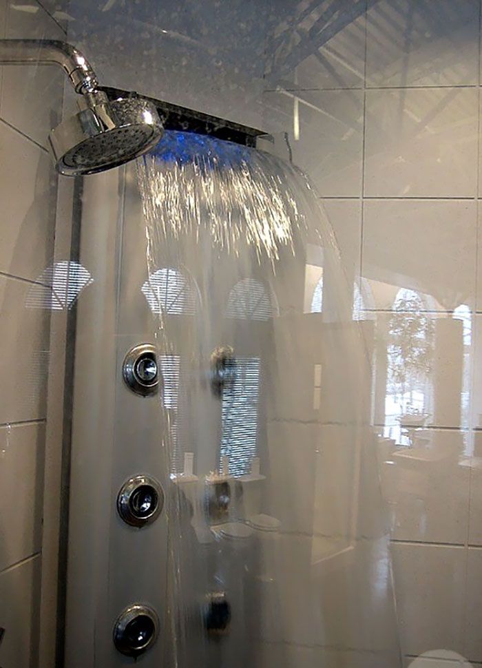 the shower head is shown in front of tiled walls and flooring, with water flowing from it