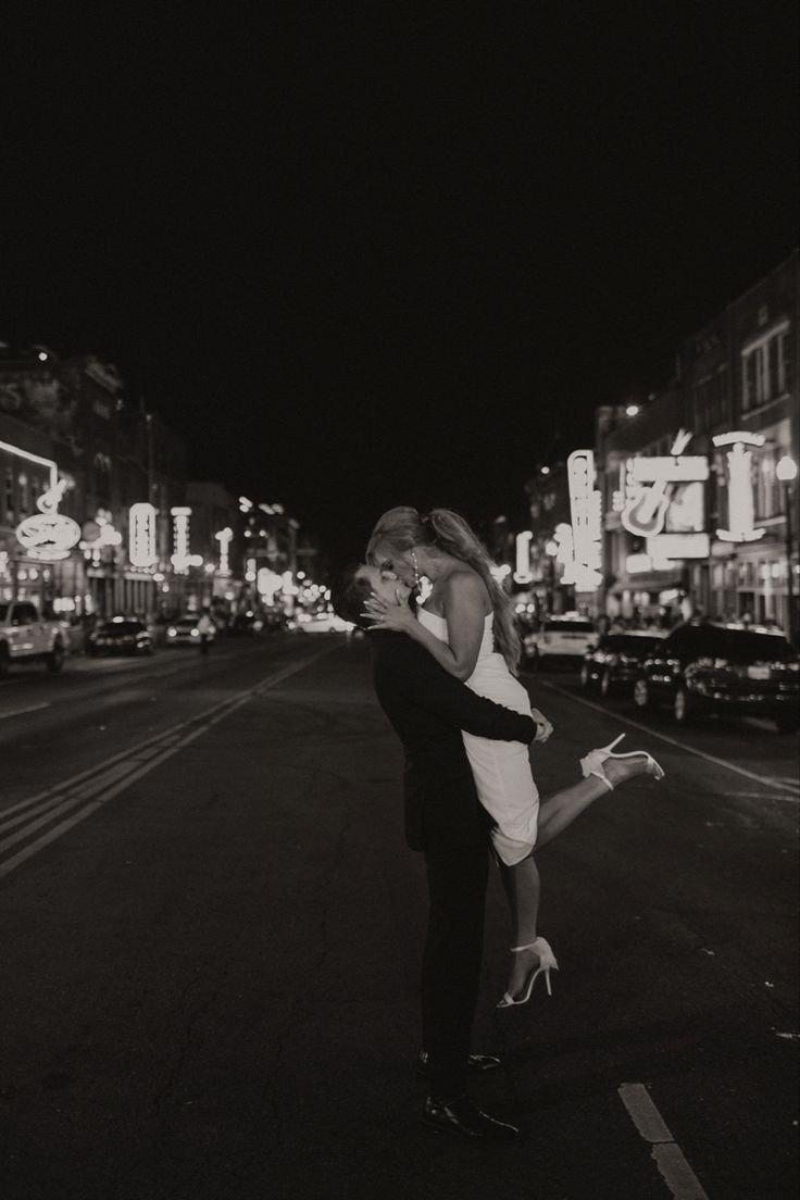 black and white photograph of couple kissing in the middle of an urban street at night