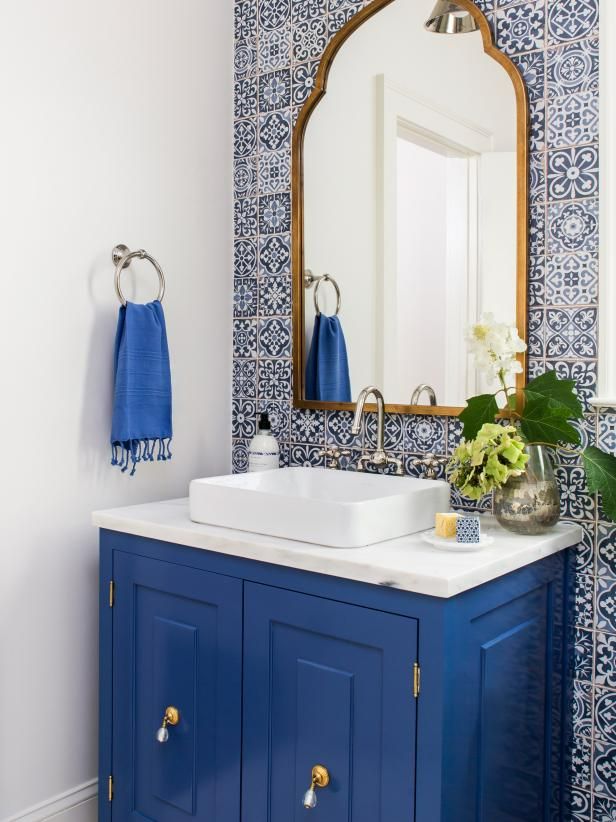 a bathroom with blue and white tiles on the walls, sink and mirror in it