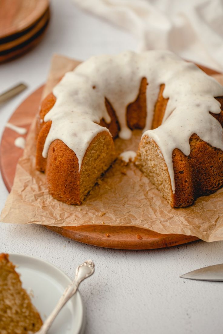 a bundt cake with white icing sitting on top of a wooden plate