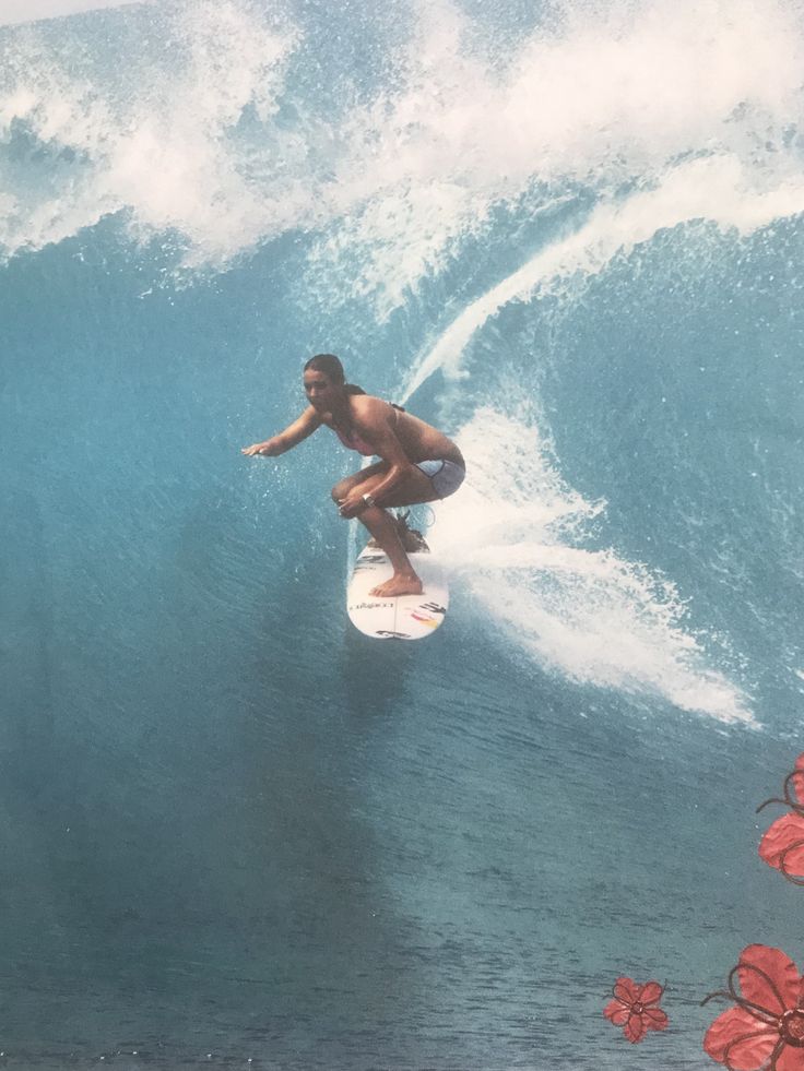 a man riding a wave on top of a surfboard in the ocean with red flowers