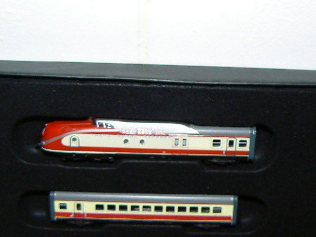 two red and white train cars sitting on top of a black shelf next to each other