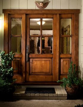 a wooden front door with glass panels and potted plants