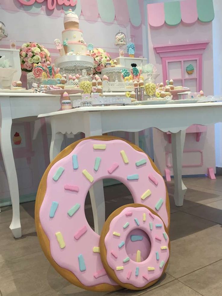 a giant doughnut sitting on top of a table next to a cake and cupcake display