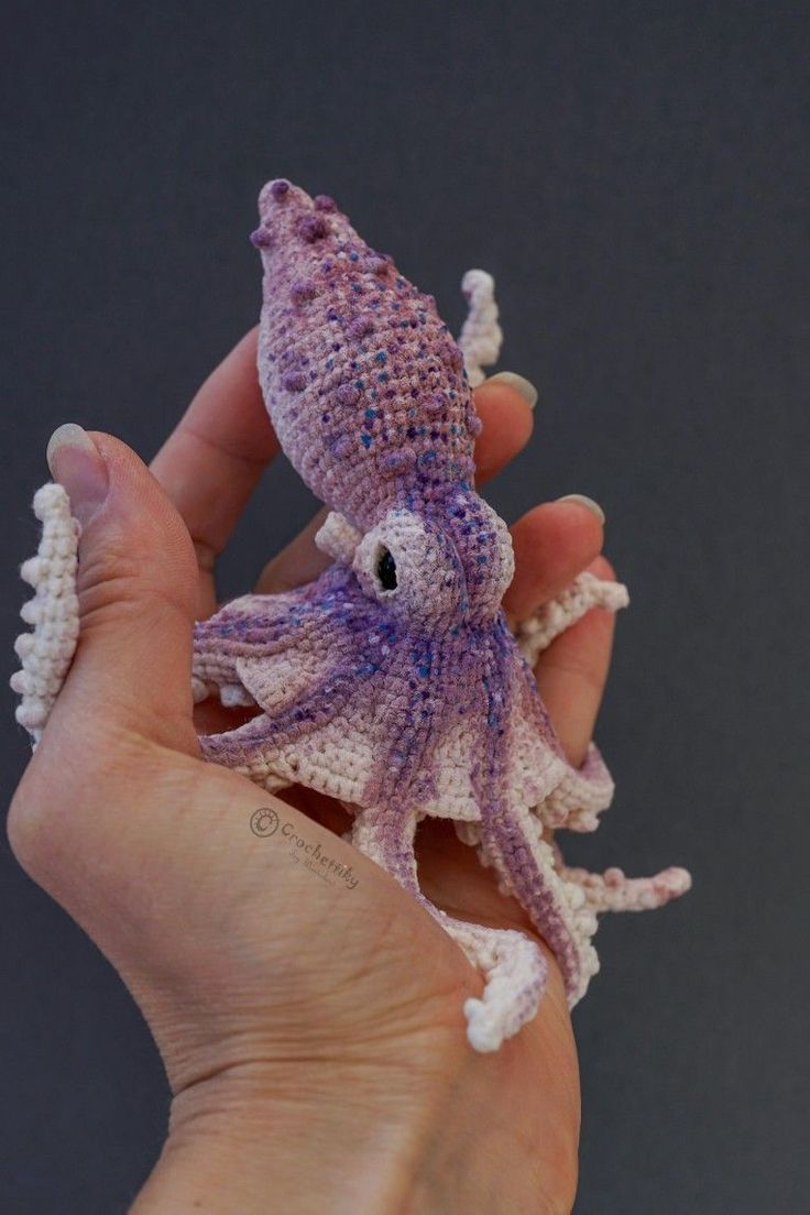 a hand holding an octopus toy in it's palm