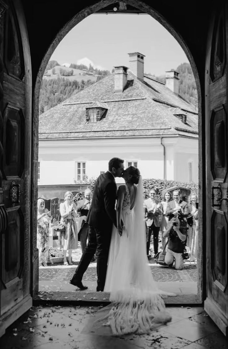 a bride and groom kissing in an open doorway