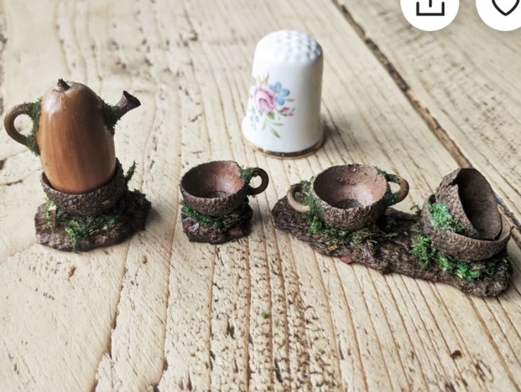 three miniature teapots are sitting on the floor next to a cup and saucer