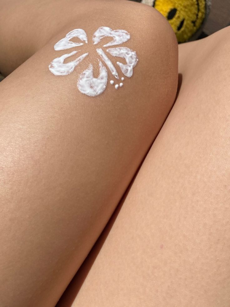 a woman's legs with white paint on them and a teddy bear behind her