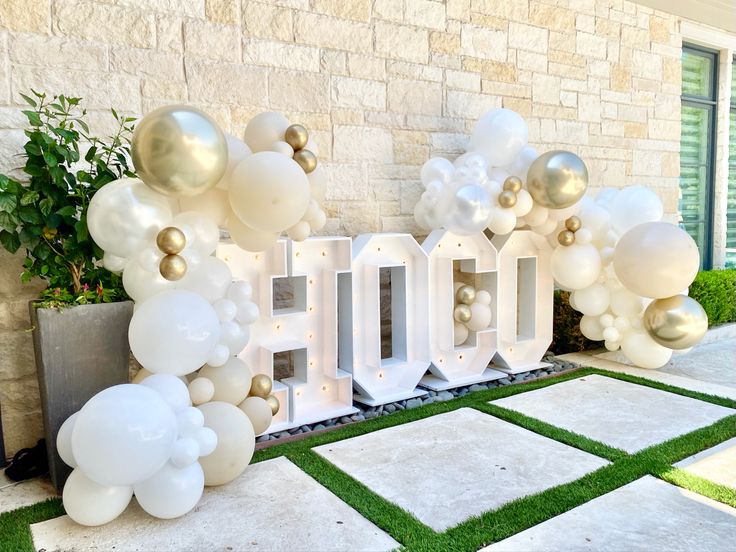 balloons are arranged around the letters that spell out hol - o in front of a brick building