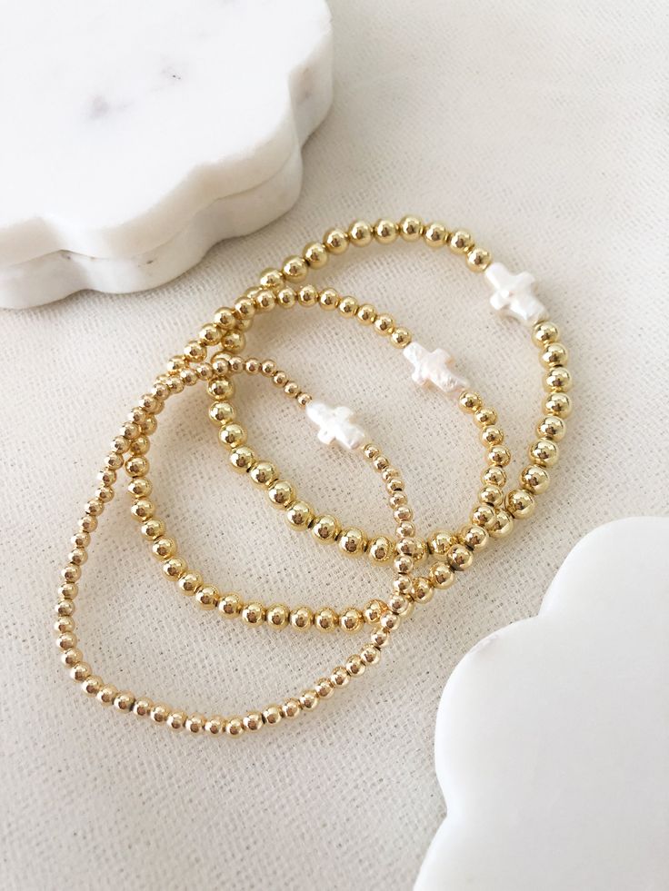 ☞ Features  ✤ Dainty, and beautiful cross shaped freshwater pearl on a 14k gold layered beaded bracelets. ✤ Choose your bead size and adjust it to your wrist in the drop- box.  ✤ The beads are made of a thick and sturdy 18k gold plated material.  ✤ Gently Handmade and Polished  ☞ Shipping ✤ Packages are sent out in 1-2 days after orders are placed from Monday through Saturday. ✤ All orders come ready to gift in our beautiful packaging. ✤ I have tried to design our packaging to be as sustainable Delicate Gold Hand-strung Beaded Bracelets, Delicate Hand-strung Gold Beaded Bracelets, Delicate Handmade Gold Beaded Bracelets, Dainty Hand-strung Stretch Bracelet, Dainty Gold Bead Bracelets For Gifts, Delicate Adjustable Gold Beads Bracelet, Dainty Hand-strung Bracelets With Round Beads, Delicate Beaded 14k Gold-filled Bracelets, Gold Delicate Stackable Beaded Bracelets