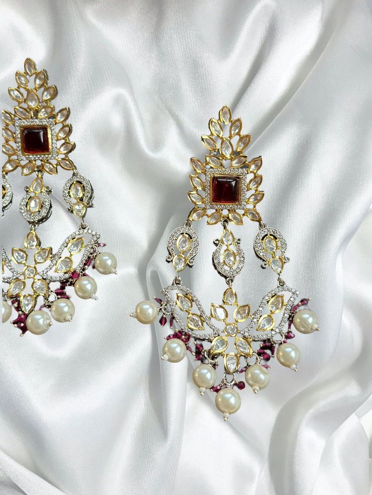 Introducing our exquisite Gold Indian Earrings adorned with radiant rubies and mesmerizing uncut polki, a true testament to timeless elegance and traditional craftsmanship. These captivating earrings are designed to enhance your beauty and add a touch of regal charm to any ensemble. 🌟 Features: 🔸 Material: High-quality gold-plated metal 🔸 Gemstones: Rich red rubies and sparkling uncut polki 🔸 Length: Gracefully long, these earrings dangle elegantly 🔸 Colors: Available in three enchanting sh Elegant Kundan Bridal Earrings With Cutdana, Elegant Bridal Earrings With Kundan And Cutdana, Formal Kundan Chandbalis With Meenakari, Elegant Festive Chandelier Earrings With Cutdana, Elegant Festive Cutdana Chandelier Earrings, Ruby Chandbali Earrings With Stone Work, Elegant Red Ruby Jhumkas, Elegant Bridal Earrings With Cutdana For Festive Occasions, Festival Celebration Ruby Chandbalis