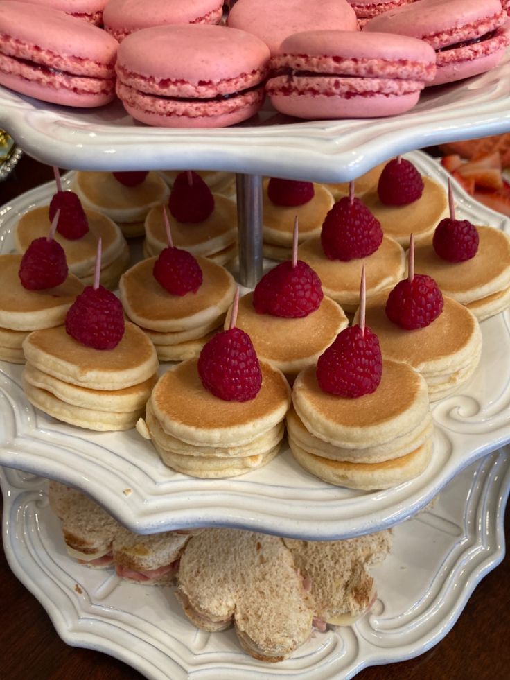 three tiered trays filled with pastries and raspberries on top of each other