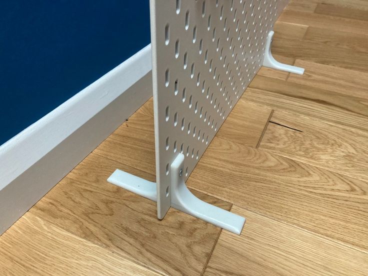 the corner of a room with a metal rack on it's side next to a hardwood floor