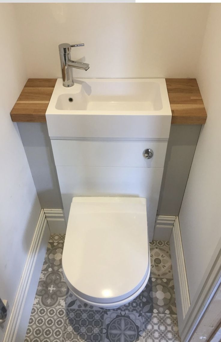 a white toilet sitting in a bathroom next to a wooden counter top under a faucet