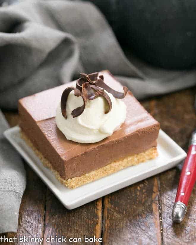 a piece of chocolate cake with whipped cream on top is sitting on a white plate