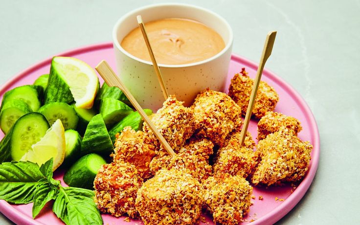 a pink plate topped with food and dipping sauce