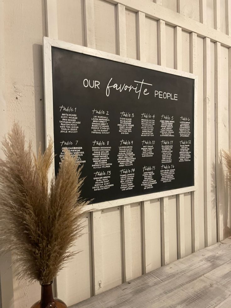 two vases with dry grass in front of a chalkboard on the side of a building