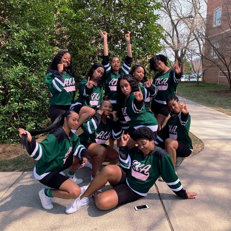 the cheerleaders are posing for a group photo on the sidewalk in front of some trees