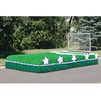 a soccer field made out of fake grass in the middle of a parking lot with trees behind it