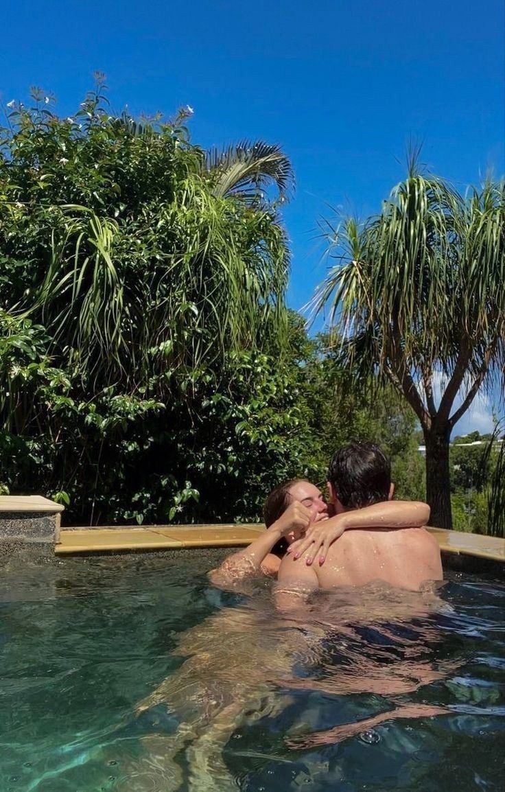 two people are in the water near some palm trees and one is holding his head