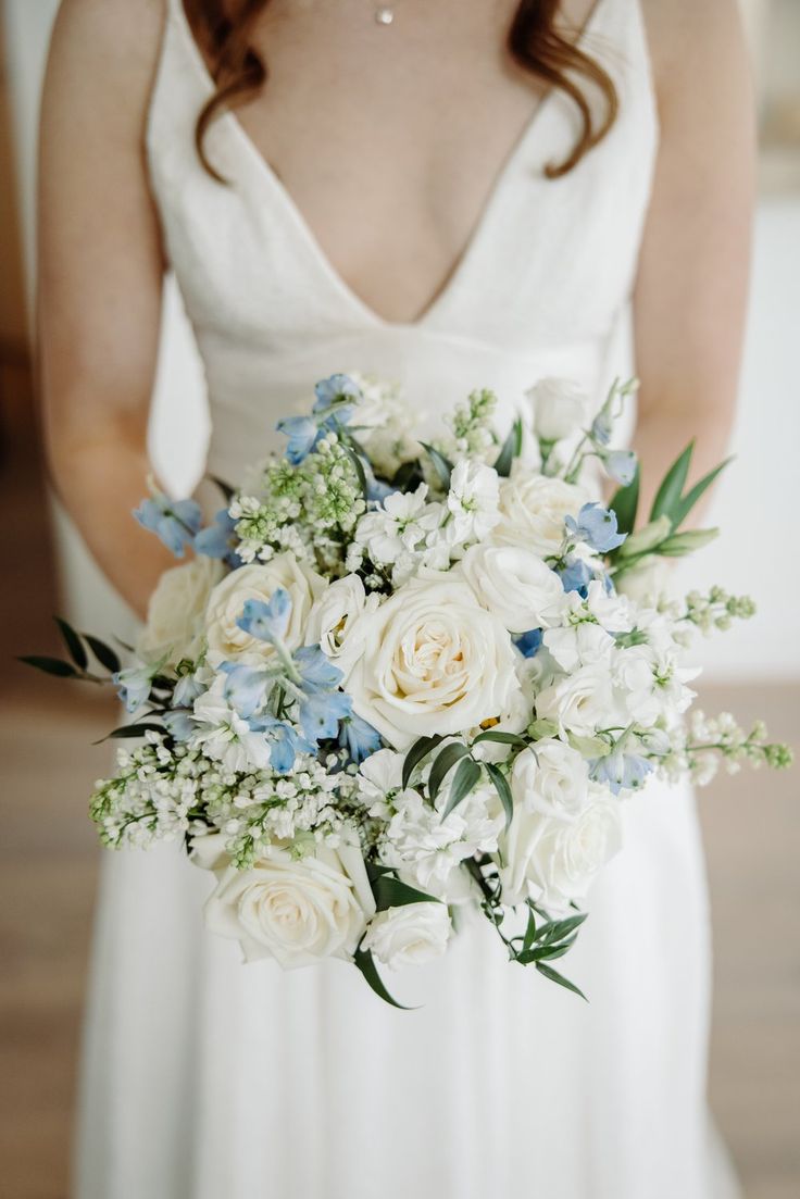 a bride holding a bouquet of white and blue flowers