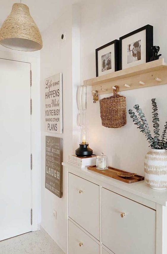 a room with white cabinets and pictures hanging on the wall next to a shelf filled with plants